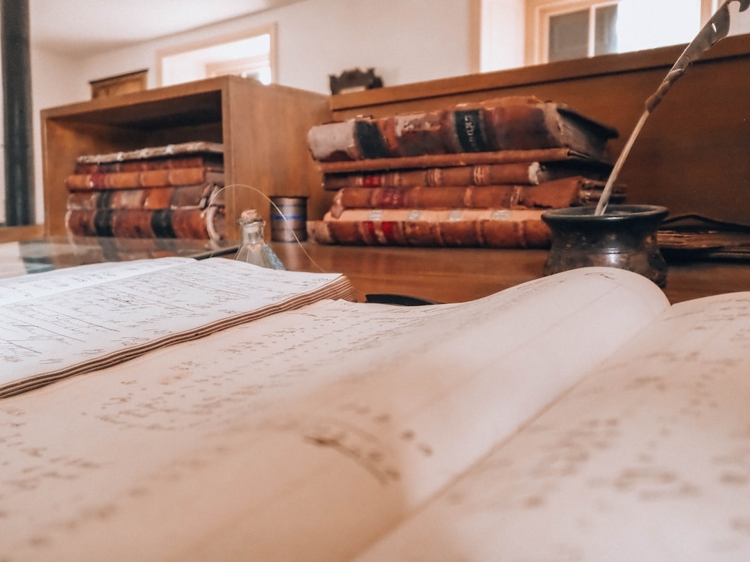 Open book, old books, and a quill on a desk.