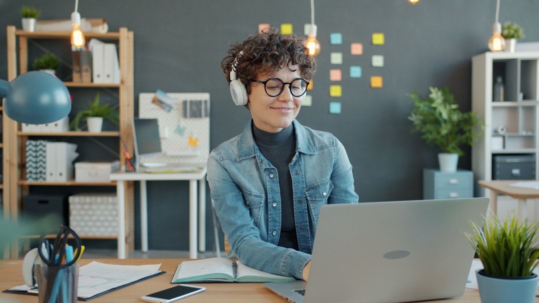 Young woman wearing headphones works on laptop in office